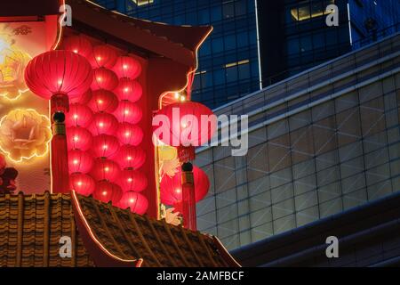 Chinesische rote Laternen lunare Neujahrsdekorationen hängen auf dem Tempeldach mit Gebäude im Hintergrund. Stockfoto