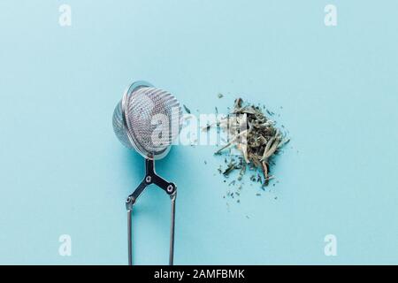 Blauer Hintergrund, Sieb und gegossen eine Handvoll Tee Bai Hao Yin Zhen Silver Nadeln, nützliche Eigenschaften von Tee, erhöht das Immunsystem und stellt e zur Verfügung Stockfoto