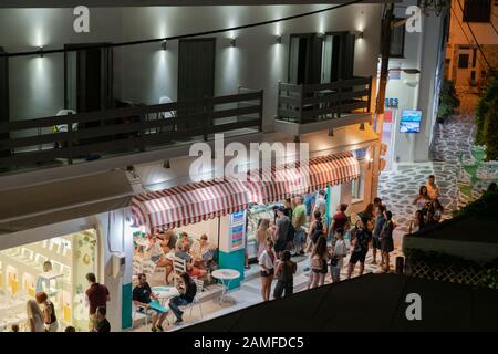 Naxos Griechenland - 11. August 2019; Menschen drängen sich im Café und Waffelgeschäft in der Straße darunter. Stockfoto