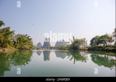 See mit Kalkkarsthügeln Nebellandschaft, die sich im Fluss in Yangshuo, Provinz Guangxi, China widerspiegelt Stockfoto