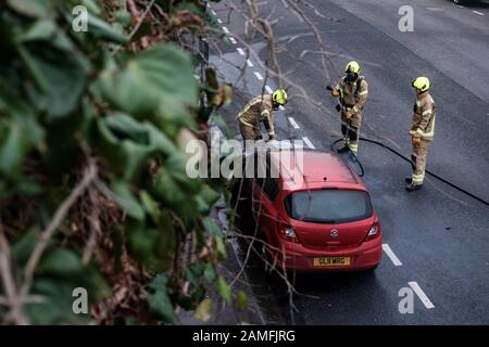 Mitglieder des Kent Fire and Rescue Service löschen einen Autobrand auf Rochester Esplanade, Kent, England, Großbritannien Stockfoto