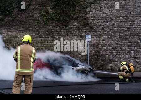 Mitglieder des Kent Fire and Rescue Service löschen einen Autobrand auf Rochester Esplanade, Kent, England, Großbritannien Stockfoto