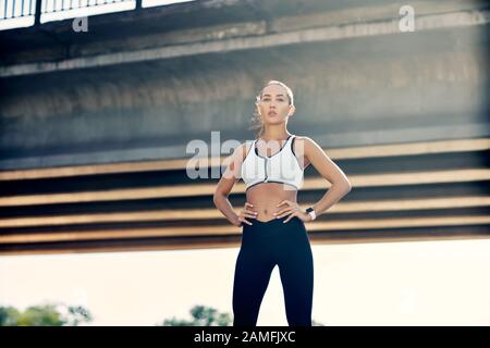 Schöne selbstbewusste Frau in Sportbekleidung, die im Freien posiert. Schönheits- und Sportkonzept Stockfoto
