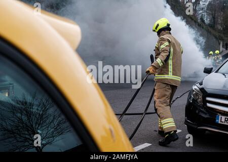 Mitglieder des Kent Fire and Rescue Service löschen einen Autobrand auf Rochester Esplanade, Kent, England, Großbritannien Stockfoto