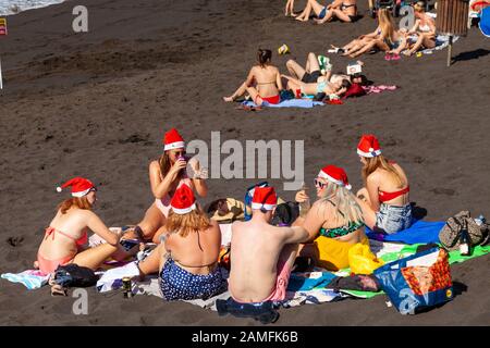 Menschen tragen Nikolausmützen auf Strand Playa de la Arena, Puerto de Santiago, Teneriffa, Kanarische Inseln, Spanien Stockfoto