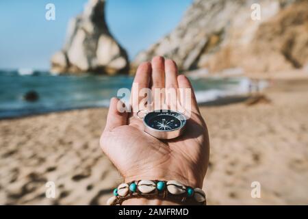 Man Hand mit Kompass Symbolling Adventure-seeking Konzept gegen Ursa Beach, Sintra, Portugal Stockfoto