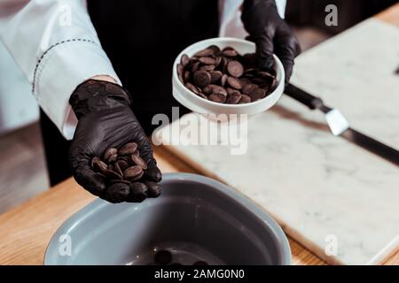 3/4-Blick auf Chocolatier, der dunkle Schokoladenchips in der Hand hält Stockfoto