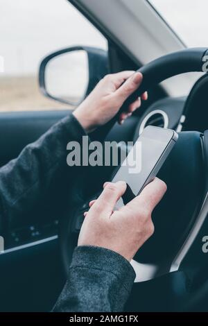 Texting und Fahren ist gefährlich Verhalten im Verkehr, in der Nähe der weiblichen Hand Eingeben von SMS auf Handy, während sie durch die Landschaft zu reisen Stockfoto