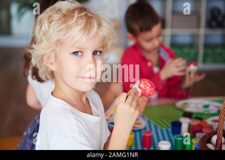 Porträt eines lächelnden Jungen, der Ostereier malte Stockfoto