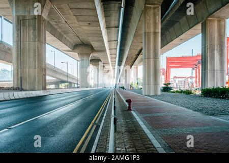 Straße unter erhöhter Autobahnbrücke, riesige Straßenüberführung Stockfoto