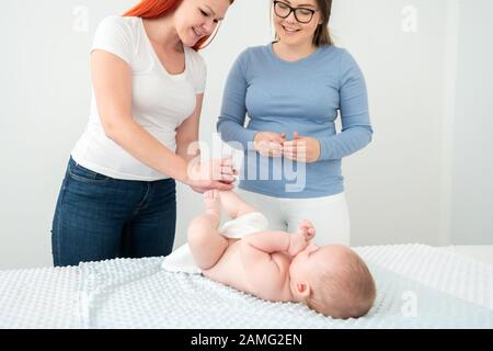 Weibliche Massage therapist Lehre junge Mutter wie Ihr neugeborenes Baby zu massieren. Baby Massage Konzept. Stockfoto