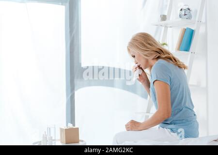 Kranke Frau, die auf dem Bett sitzt und Serviette hält Stockfoto