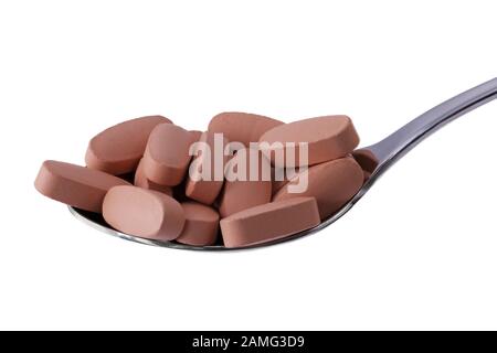 Vitaminpillen auf Esslöffel isoliert auf Weiß. Makrofotografie, Nahrungsergänzungsmittel. Konzept für Ernährung, Gesundheit und Ernährung. Stockfoto