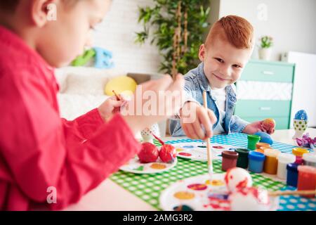 Lächelnder Junge, der Ostereier malt Stockfoto