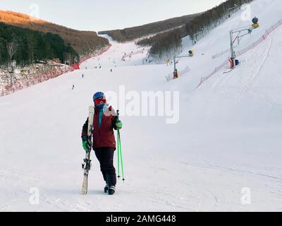 (200113) -- PEKING, 13. Jan. 2020 (Xinhua) -- Xiao Zhen hält Skistafeln und Stöcke auf einem Skigebiet im Chongli-Viertel der Stadt Zhangjiakou in der nordchinesischen Provinz Hebei, 12. Januar 2020. Xiao Zhen, Mitarbeiter eines Pekinger Internetunternehmens, ist seit vier Jahren auf dem Skifahren interessiert und fährt immer auf die Skigebiete im Chongli-Viertel der Stadt Zhangjiakou in der nordchinesischen Provinz Hebei. Laut Xiao verbrachte Sie früher vier bis fünf Stunden damit, einen Lift zu stumpfen oder einen Bus nach Chongli aus Peking zu nehmen. Der kürzliche Betrieb der Schnellfahrstrecke Beijing-Zhangjiakou reduzierte den reisetempo Stockfoto