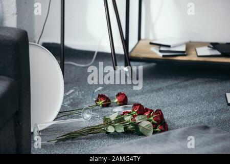 Blumen und zerbrochene Vase auf dem Boden in raubter Wohnung Stockfoto