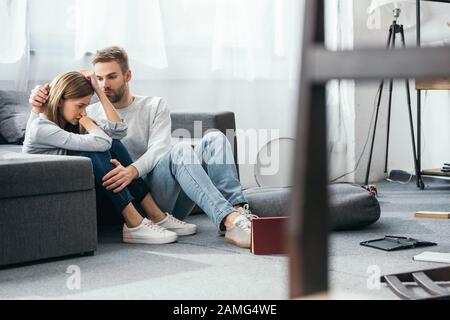 Gutaussehender Mann beruhigt traurige Frau in geraubter Wohnung Stockfoto