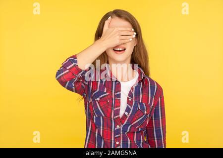 Ich beobachte nicht. Porträt des Ingwermädchens in Hemd, das die Augen mit der Hand bedeckt und mit offenem Mund steht, überrascht, dass Angst nicht aussehen will. In Stockfoto