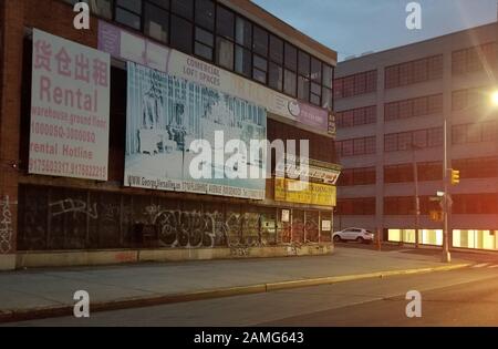 Graffiti-bedecktes Gebäude mit veralteter und alternder Werbung in der Abenddämmerung, an der Ecke Flushing Avenue und Cypress Avenue in Bushwick, Brooklyn, 16. April 2019. () Stockfoto