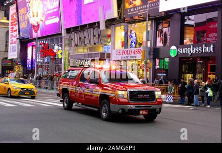Ein FDNY GMC-Feuerwehrwagen fährt durch Den Times Square bei Twilight, Broadway, New York City, USA 2018. Stockfoto
