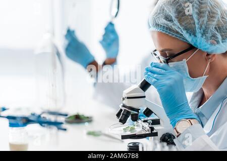 Selektiver Fokus des Biologen mit Mikroskop und afroamerikanischer Kollege mit Lupe Stockfoto