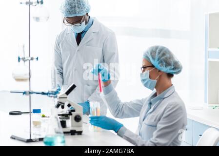 Multikulturelle Biologen in weißen Mänteln, die im Labor getestet werden Stockfoto