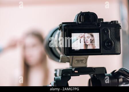 Selektiver Fokus des Assistenten, der mit attraktivem Modell auf der Kamera-Anzeige im Fotostudio arbeitet Stockfoto