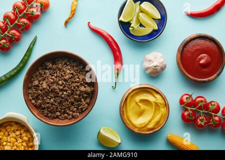 Draufsicht auf Hackfleisch in Schüssel mit frischem Gemüse und Kalk auf blauem Grund Stockfoto