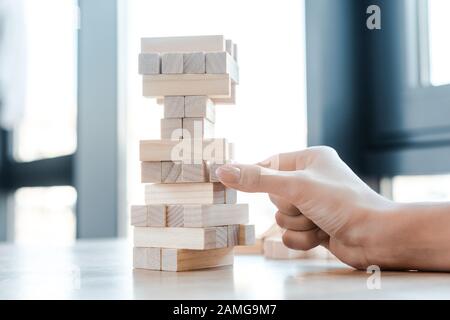 Kiew, UKRAINE - 22. NOVEMBER 2019: 3/4-Ansicht der Frau, die Block-Holz-Tower-Spiel spielt Stockfoto