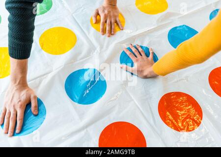 Kiew, UKRAINE - 22. NOVEMBER 2019: Zugeschnittene Ansicht von Mann und Frau, die beim Spielen von Twister-Spielen die Hände auf die Kreise legen Stockfoto