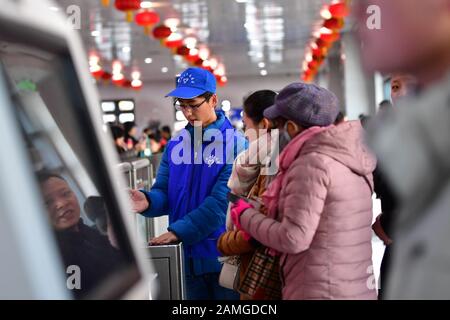 (200113) -- LANZHOU, 13. Januar 2020 (Xinhua) -- EIN Freiwilliger hilft Passagieren, durch das automatische Eingangstor am Bahnhof Lanzhou in Lanzhou, der Hauptstadt der nordwestchinesischen Provinz Gansu, am 13. Januar 2020 zu gelangen. Während der Reiseströme des Frühlingsfestes wurde am Bahnhof Lanzhou und am Westbahnhof von Lanzhou ein spezieller Freiwilligendienst mit dem Namen "Wegwerf der Reise" veranstaltet. Für Fahrgäste, die Termine vereinbart haben, die in Eile sind, um in die Züge zu kommen oder das mobile Ticketsystem nicht kennen, sind Freiwillige da, um Dienst zu leisten und ihnen zu helfen, die Zeit des Zugs zu verkürzen, B. Stockfoto