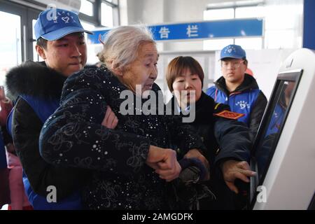 (200113) -- LANZHOU, 13. Januar 2020 (Xinhua) -- Freiwillige helfen einer älteren Frau, ihren vorläufigen Personalausweis am Bahnhof Lanzhou in Lanzhou, der Hauptstadt der nordwestchinesischen Provinz Gansu, am 13. Januar 2020 auszudrucken. Während der Reiseströme des Frühlingsfestes wurde am Bahnhof Lanzhou und am Westbahnhof von Lanzhou ein spezieller Freiwilligendienst mit dem Namen "Wegwerf der Reise" veranstaltet. Für Passagiere, die Termine vereinbart haben, die in Eile sind, um in die Züge zu kommen oder das mobile Ticketing-System nicht kennen, sind Freiwillige da, um Service zu bieten und ihnen zu helfen, die Zeit des Zugs zu verkürzen, br Stockfoto