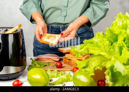 Mädchen hält gebratenes Brot in den Händen, um ein Sandwich zu machen Stockfoto