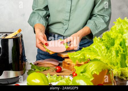 Das Mädchen hält eine fertige Schicht Sandwich in den Händen. Stockfoto