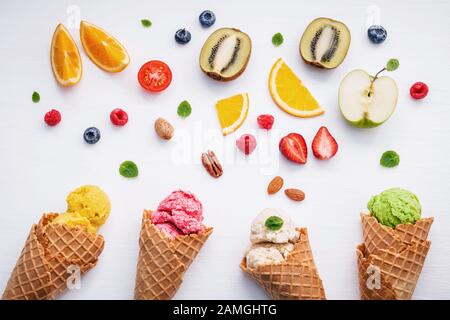 Set von Eisschaufeln in verschiedenen Farben und Geschmacksrichtungen mit Beeren, Nüssen und Früchten Dekoration isoliert auf weißem Hintergrund Stockfoto