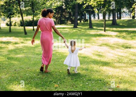 Zurück Blick von Mutter und Tochter läuft Hand in Hand in einem Park Stockfoto