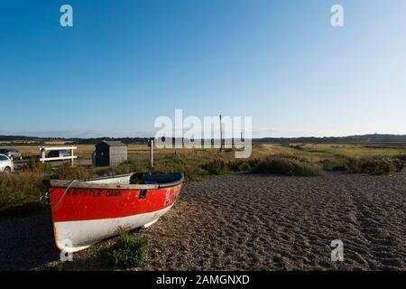 Ein rotes und weißes Fischerboot am Strand von Cley Next The Sea, North Norfolk, Großbritannien Stockfoto