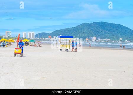 Guaruja - SP, Brasilien - 19. November 2019: Menschen am Strand, die einen sonnigen Tag am Sand und am Meer genießen. Einige Lebensmittelhändler in der Nähe. Brasilianisches Touris Stockfoto