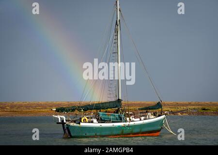 Rainbow über einem Fischerboot, das an der Flussmünde in der Nähe von Wells-next-the-Sea, Norfolk, England, festgemacht wurde Stockfoto