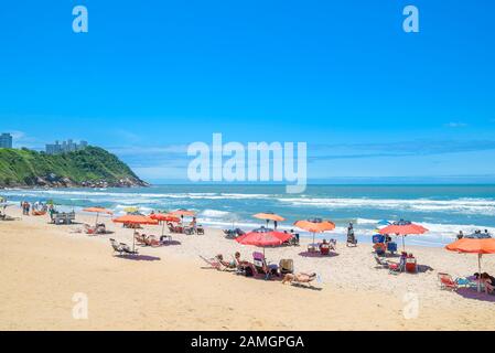 Guaruja - SP, Brasilien - 20. November 2019: Schöner Brasilienstrand an der Paulista-Küste an einem sonnigen Tag. Sonnenbäder, Sonnenschirme und die wunderbare Aussicht Stockfoto