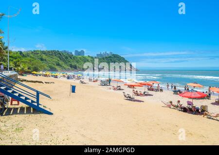 Guaruja - SP, Brasilien - 20. November 2019: Schöner Brasilienstrand an der Paulista-Küste an einem sonnigen Tag. Sonnenbäder, Sonnenschirme und die wunderbare Aussicht Stockfoto