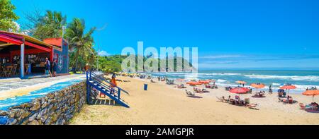 Guaruja - SP, Brasilien - 20. November 2019: Brasilianischen Strand der Paulista-Küste. Panoramablick auf ein Strandrestaurant und Sonnenanbeter Stockfoto