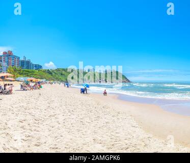 Guaruja - SP, Brasilien - 20. November 2019: Schöner Brasilienstrand an der Paulista-Küste an einem sonnigen Tag. Sonnenbäder, Sonnenschirme und die wunderbare Aussicht Stockfoto