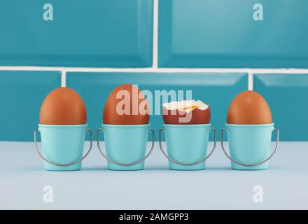 Vier gekochte Eier in Eimereggcups in blauer Küche Stockfoto