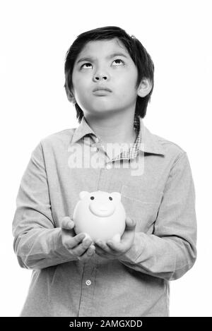 Studio shot von cute Japanese boy Holding piggy Bank beim Denken Stockfoto