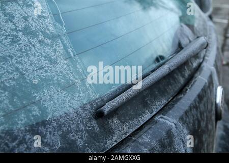 Die Details einer Heckscheibe und eines Wagens während der Wintersaison, schmutzig aus dem Salz oder der Sole, die gegen Schnee und Eis auf den Straßen verwendet wird. Stockfoto