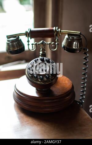 Nahaufnahme des antiken Telefontelefons aus Holz und Messing auf dem Zimmertisch. Koloniales Dekor-Konzept. Stockfoto