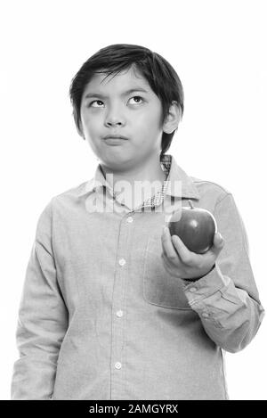 Studio shot von cute Japanese boy holding red apple beim Denken Stockfoto