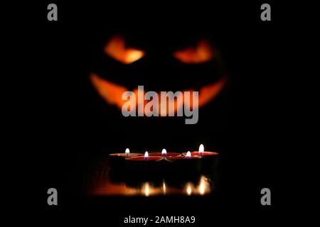 Frohes Halloween-Konzept. Fünf Kerzen auf dem Tisch über dem gruseligen Kürbiskopf Dekoration Hintergrund. Nahaufnahme. Textbereich. Innenschuss Stockfoto