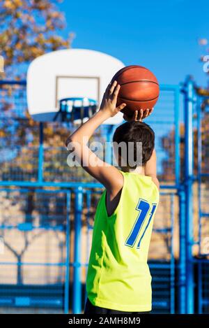 Jugendliche werfen einen Basketball in den Bügel von hinten Stockfoto